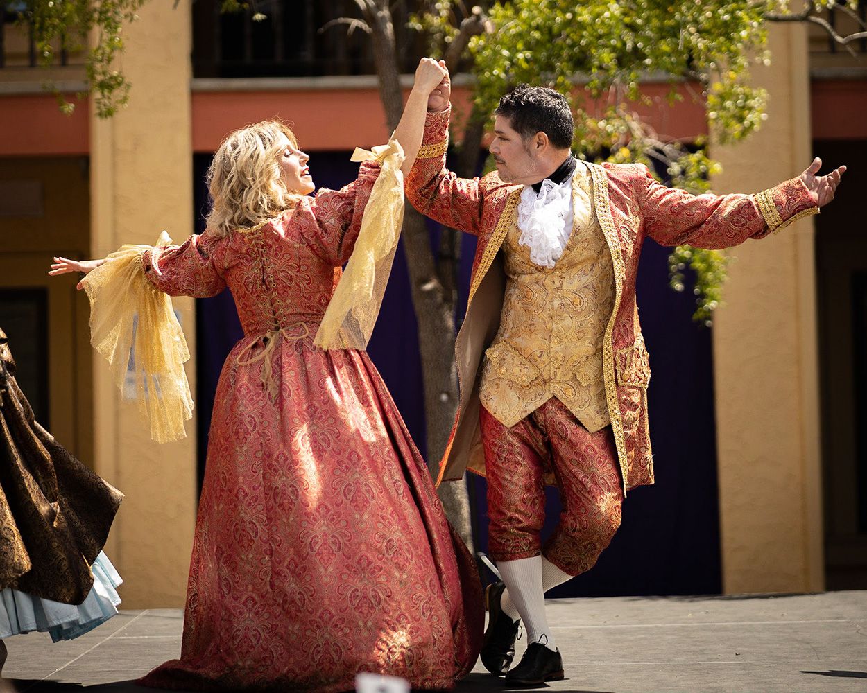 dancing couple dressed in matching venetian outfits in red and gold. 
