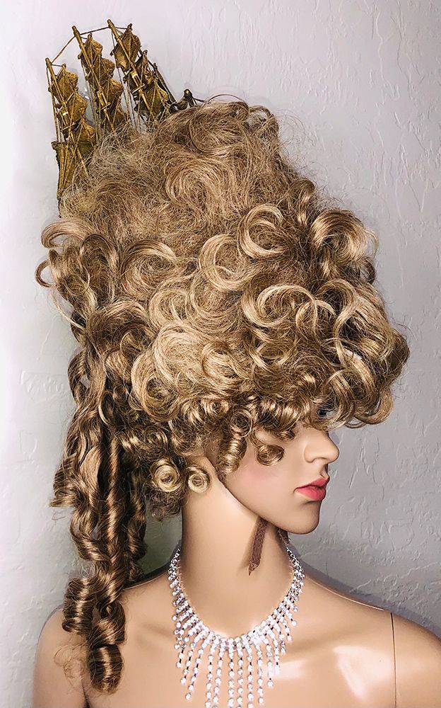 mannequin in a big blonde french-court-style updo with a golden ship on top