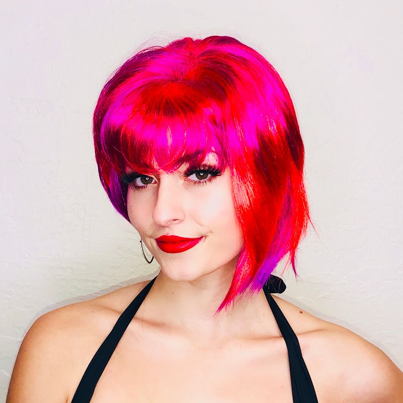 smiling model in a short hot pink asymmetrical wig with bangs