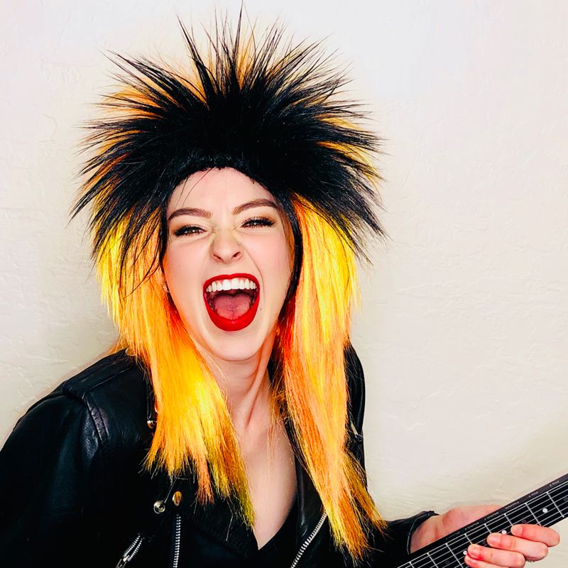 model playing guitar while in a black and yellow rocker mullet wig