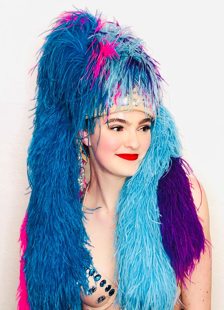 model in multi-colored feathered headpiece and sequined bra top